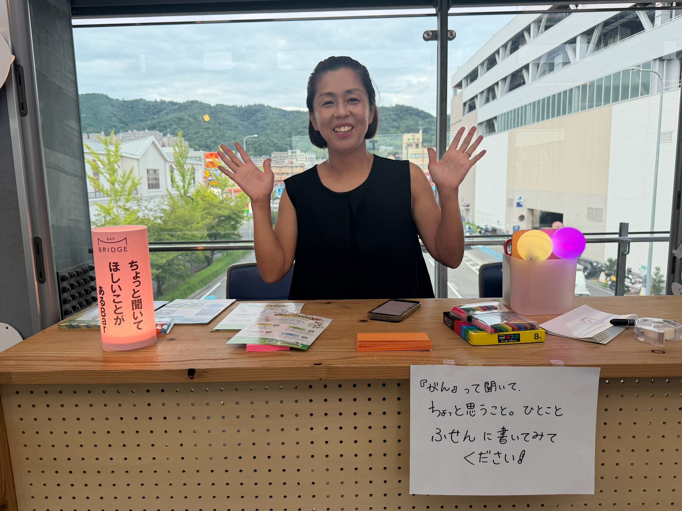 ふせんとペンを並べたテーブルで笑顔で迎える様子
